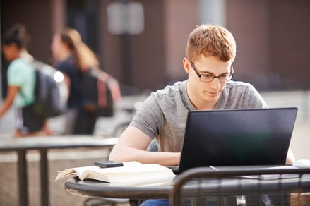 Young male college student working on laptop at campus